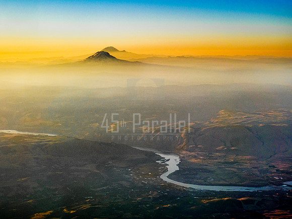 The city of The Dalles, Oregon, nestled in the curve of the Columbia River, with Mt. Adams and Mt. Rainier standing watch.